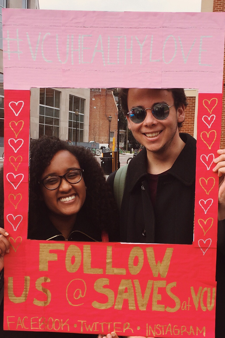Nardos Iyob and other student pose behind a posterboard cutout promoting the VCHHealthyLove social media hastag