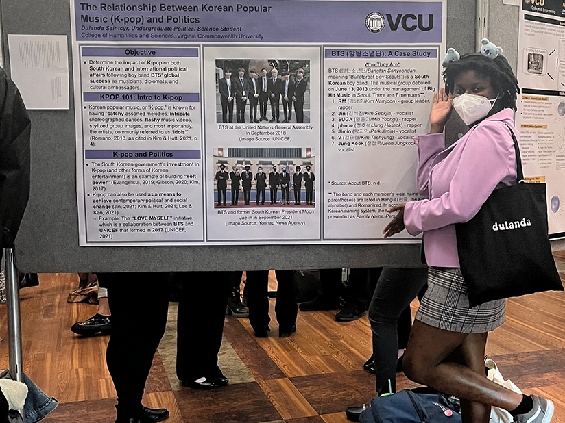 Duland Saintcyr stands in front of a research poster presentation