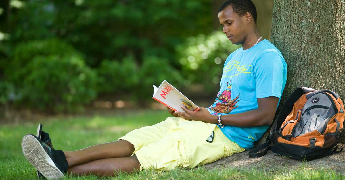 a v.c.u. student sitting under a tree reading a book